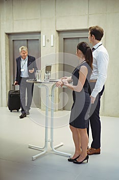 Executives standing with glasses of water to welcome their colleague