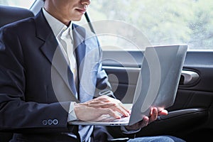 Executives use laptops to work while traveling and sitting inside the car