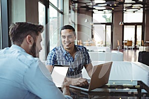 Executives using laptop and digital tablet in cafÃÆÃÂ©