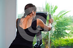 Exercise bike cardio workout at fitness gym of woman taking weight loss. female listens to music on headphones. Athlete