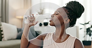 Exercise, black woman and drinking water in bottle in home, healthy diet or wellness. African athlete, thirsty or liquid