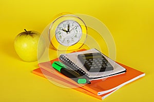 Exercise books, a notepad, calculator and apple