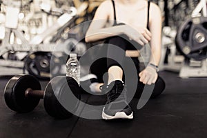 Exercise concept The female with dark tone of outfits resting herself on the black carpet floor after playing on the dumbbell