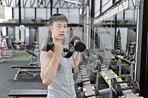 Exercise concept The male sport member lift black dumbbells up with both hands, standing and doing concentration curl posture