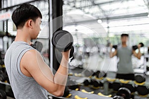 Exercise concept The male sport member lift black dumbbells up with both hands, standing and doing concentration curl posture