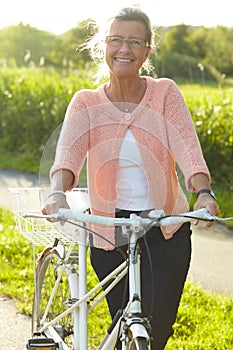 Exercise doesnt have to be strenuous. A lovely senior woman standing with her bike beneath a summer sun.