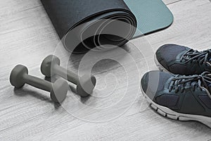 Exercise mat, sneakers and dumbbells on the light wooden floor. Active healthy lifestyle concept.