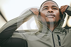 Exercise, mindset and hoodie with a sports black man getting ready for a workout, fitness or running. City, health and