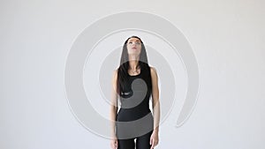 Exercises for beginners. The young woman is stretching her neck back and forward at the white background. Neck flexion