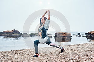 Exercises with sunrise. Side view of beautiful disabled athlete woman in sportswear with prosthetic leg standing in yoga