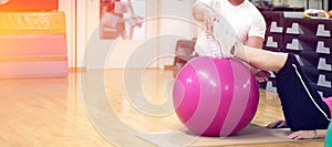 Exercising with personal trainer on large stability ball in studio fitness back