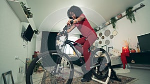 Exercycle is being used by a african-american lady for training at home. Sport from home, fitness at home.