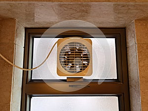 Exhaust old dusty fan in a window in a toilet with walls of marble