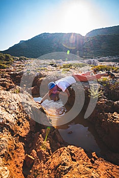 Exhausted adventurer drinks water from a crevice in a rock