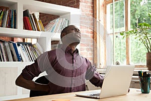 Exhausted african american male office worker having back discom