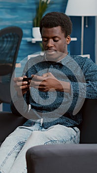 Exhausted african american man falling asleep while holding phone in his hands