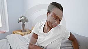 Exhausted african american woman lying bored in bed, yawning tiredly, sleepiness washing over her, hand covering her yawning mouth