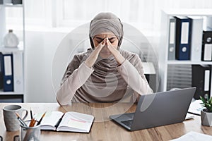 Exhausted arabic businesswoman having migraine after long time work in office