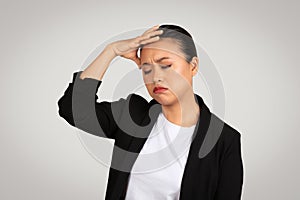 Exhausted Asian businesswoman holding her forehead in stress or headache, eyes closed