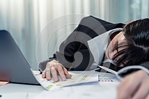 Exhausted Asian businesswoman office worker napping at workplace, feel tired of many paper work on table. Busy Employee worker gir