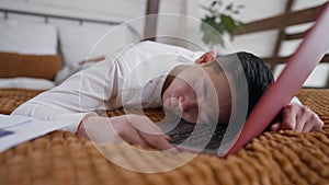 Exhausted Asian man sleeping on laptop keyboard in home office. Portrait of overworked Chinese manager napping in