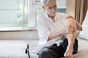 Exhausted asian senior woman hold her knee suffering from pain in knee joint,elderly patient massage her knees with hands,painful