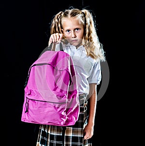 Exhausted beautiful little schoolgirl carrying a big schoolbag