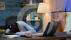 Exhausted black businesswoman falling asleep on desk