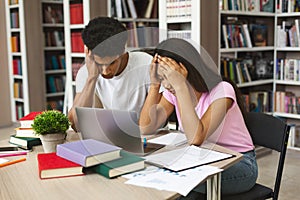 Exhausted black couple of students stucked with homework at library