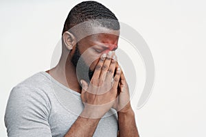 Exhausted black guy suffering from antritis, rubbing nose bridge