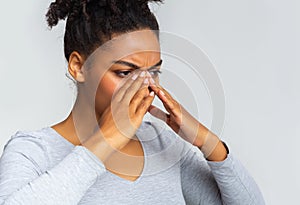 Exhausted black woman suffering from antritis, rubbing nose bridge