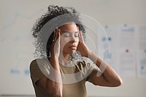 Exhausted black woman worker massage temples having headache