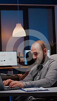 Exhausted businessman checking marketing statistics on laptop computer