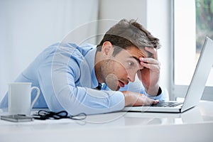 Hes buried under his work load. A exhausted businessman falling asleep behind his laptop.