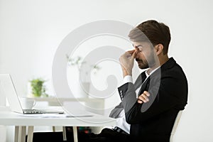 Exhausted businessman feeling tired massaging nose bridge