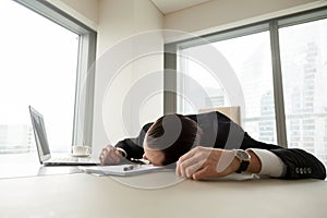 Exhausted businessman lying on his desk in office