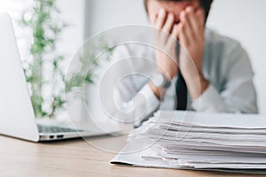 Exhausted businessman overloaded with work in office