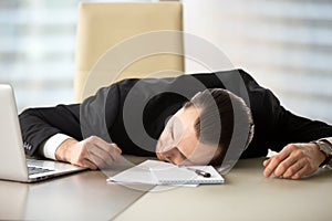 Exhausted businessman passed out at his work desk in office