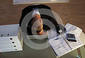 Exhausted businessman sleeping an a stack of files photo