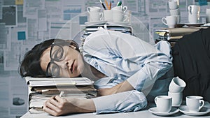 Exhausted businesswoman lying down on the desk and sleeping