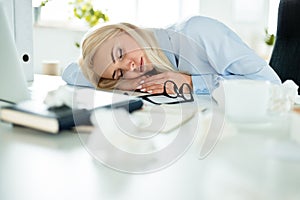 Exhausted businesswoman napping on the desk at work