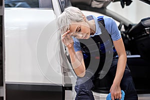 Exhausted caucasian female auto mechanic sitting insode of car after cleaning