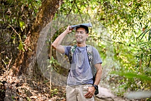 Exhausted and confused Asian male traveler holding map, get lost in the forest while trekking