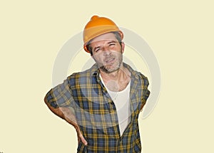 Exhausted construction worker or repair man wearing builder helmet complaining suffering pain in his lower back after working hard