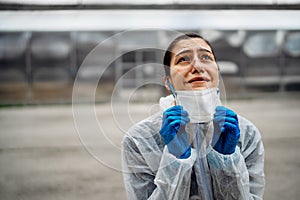 Exhausted crying doctor/nurse in coronavirus protective gear N95 mask.Covid-19 pandemic outbreak.Fatalities grief.Frontline worker