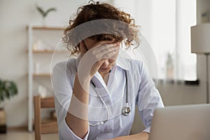 Exhausted depressed young female doctor feeling burnout at work