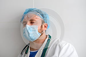 Exhausted doctor with closed eyes in face mask