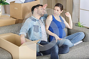 exhausted expectant couple unpacking cardboard boxes