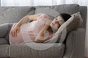 Exhausted expectant mom lying on sofa getting some sleep