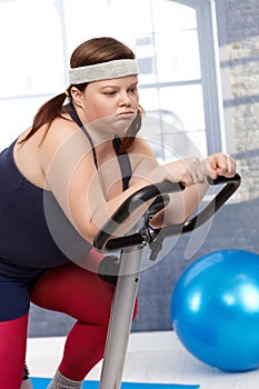 Exhausted fat woman on exercise bike